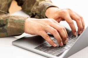 military typing on laptop