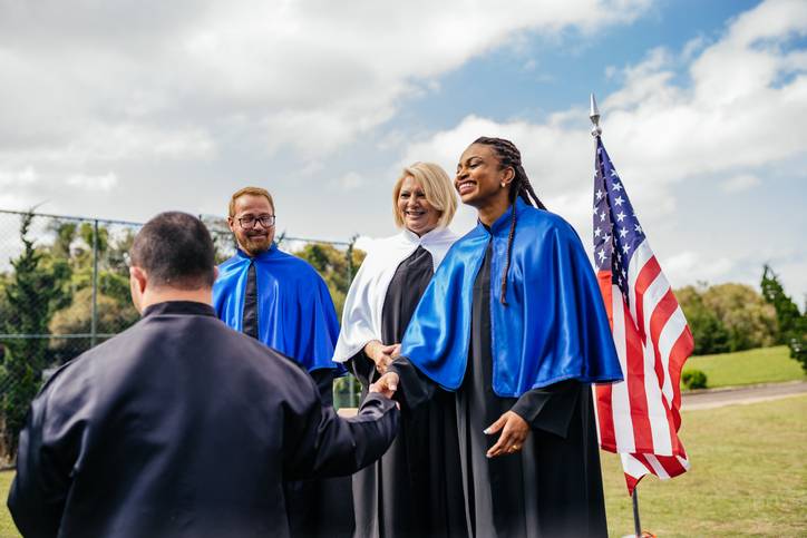 Teachers greeting a graduate outdoors