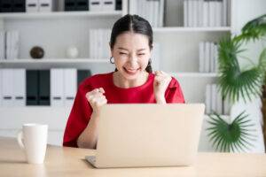 young woman celebrating on computer