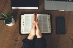 praying at home with bible and laptop