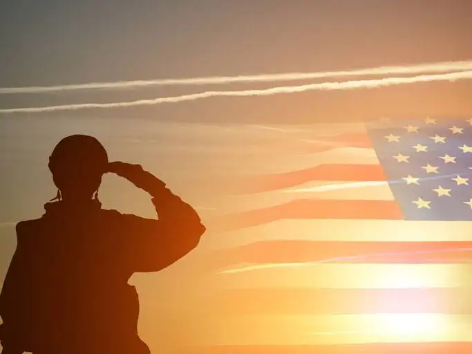 soldier saluting flag at sunrise