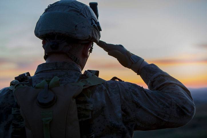soldier saluting at sunset along