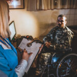 Female nurse making visit to soldier male sitting in wheelchair