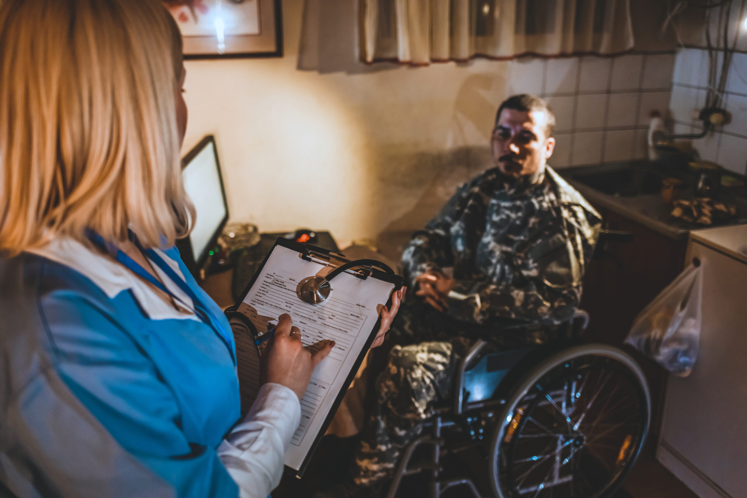 Female nurse making visit to soldier male sitting in wheelchair