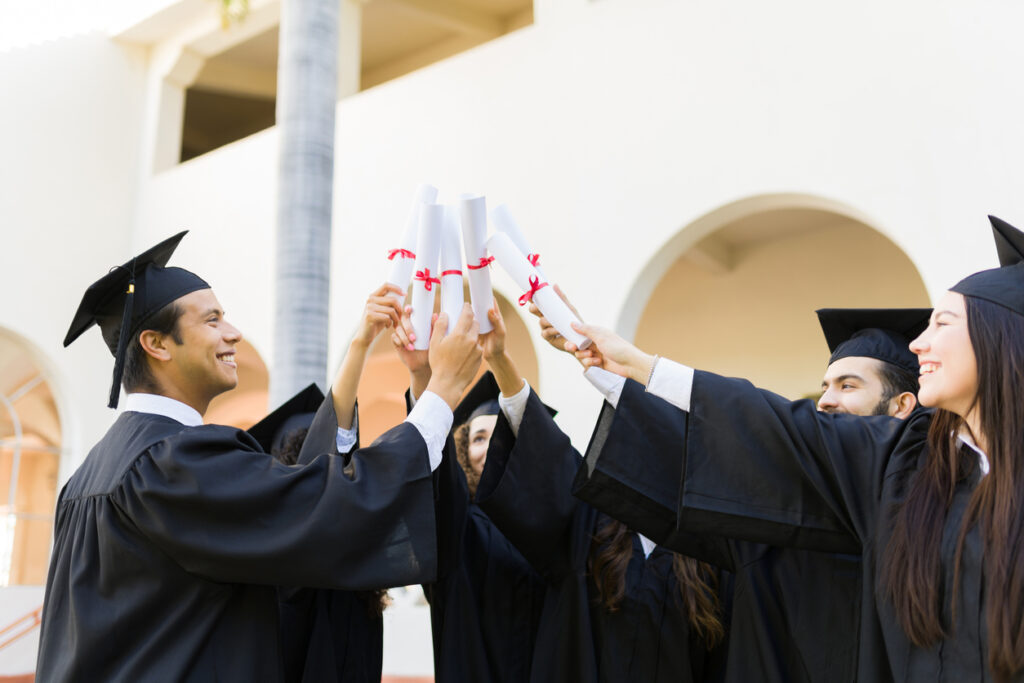 group of cheerful people at graduation, holding diplomas