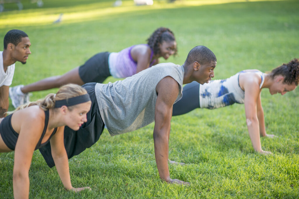 College students in an ROTC program doing planks on grass.