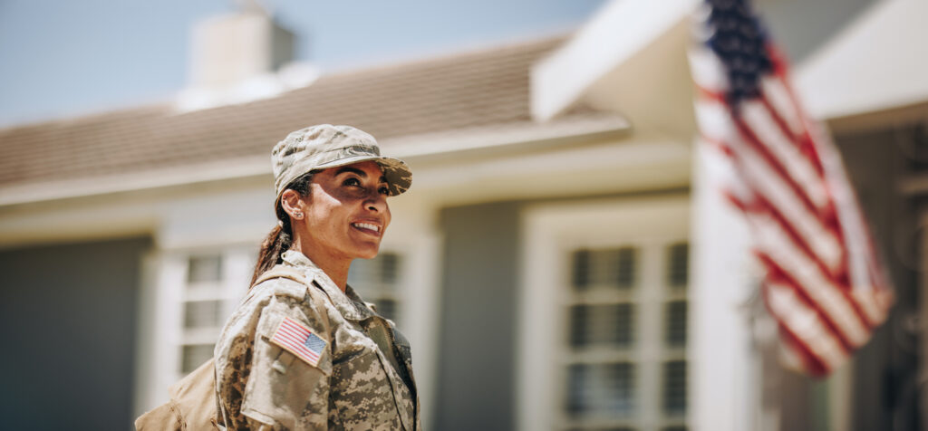 A female soldier in fatigues smiling while looking at the sky.