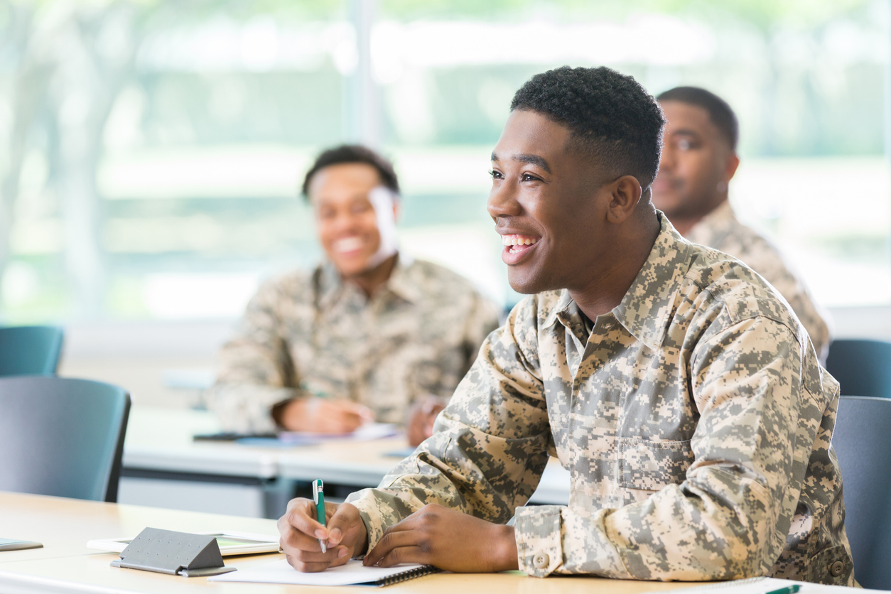 A Black soldier smiling while filling out a form.