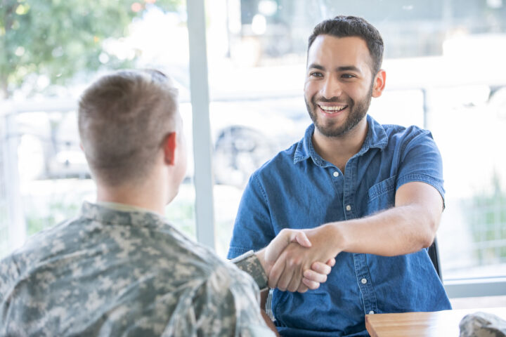Male military personnel shaking hands with an employer during an interview.